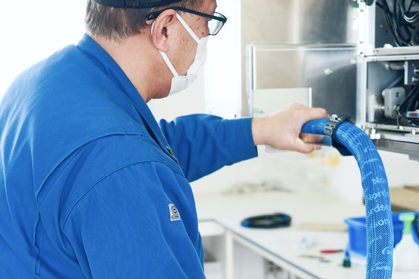 Worker attaching a blue hose to equipment